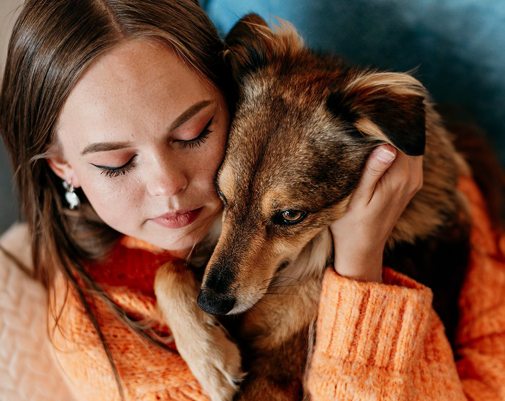 woman wearing orange sweater holds her dog in quiet moment